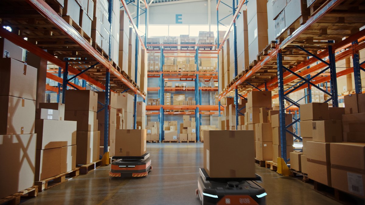 Automated guided robots moving packages in a warehouse aisle